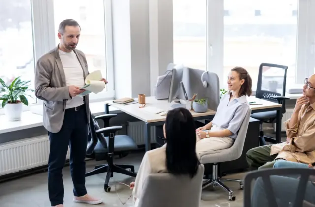 Team gathered in a bright office listening to a colleague